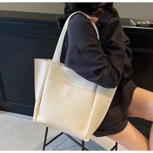 Close-up of cream tote bag featuring a front pocket and premium smooth leather texture