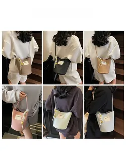 Sac seau en similicuir grainé avec bandoulière tissée et charm métallique en six coloris