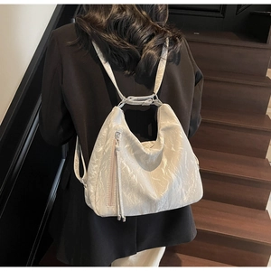 Detailed view of cream wrinkled texture backpack with long tassel zipper on a model