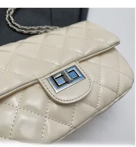 Close-up of beige quilted crossbody bag with silver twist-lock and chain strap