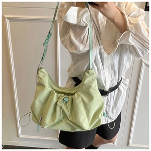 Detail of mint green nylon crossbody bag showing pleated drawstring texture and side label