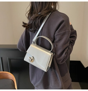 Dettaglio mini borsa argento metallizzato con patta ondulata e cuore sul modello