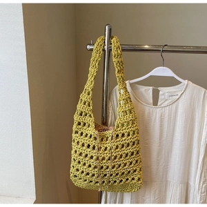Detalle del bolso de paja tejida en amarillo limón con diseño de malla y bolsa interior