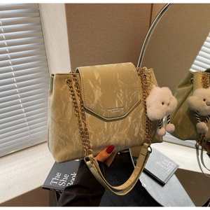 Detail of mint green textured shoulder bag with golden chain and plush cloud charm