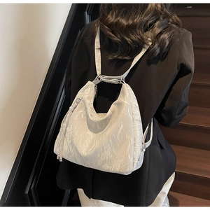 Detail view of glossy crinkled leather hobo bag with adjustable straps and metal zipper
