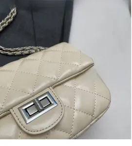 Detail of beige quilted leather bag with silver metal swivel lock and chain strap