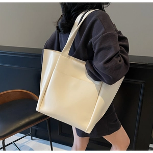 Close-up of a large beige leather tote bag with a functional front pocket and handles
