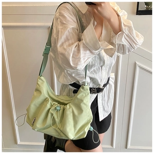 Close-up of light green nylon tote bag with drawstring pleated pocket and adjustable strap