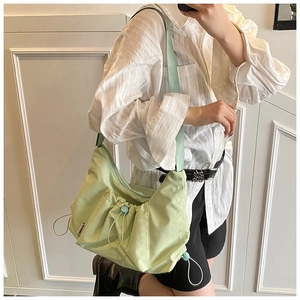 Detail view of adjustable strap buckle and drawstring fold texture on nylon tote bag