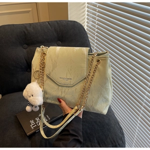 Detail of mint green marble texture leather bag with gold chain and plush cloud charm