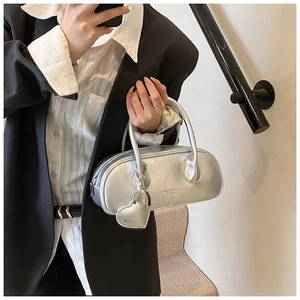 Selfie miroir d'un sac à main ovale argenté avec breloque cœur et texture métallique