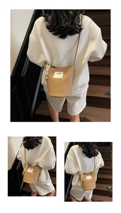 Détail du sac seau kaki avec texture grainée, logo de marque et foulard en soie rayé