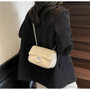 Detailed back view of a creamy white quilted chain bag with silver lock on a black blazer