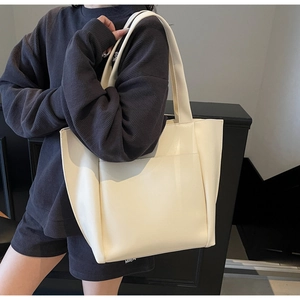 Minimalist cream tote bag styled on model with large front pocket and long shoulder straps