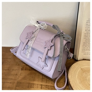 Close-up of lavender messenger bag with star patches and decorative lace bow detail