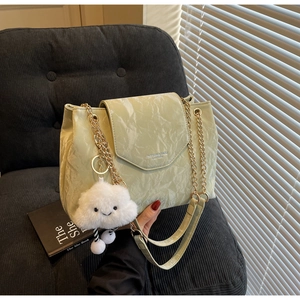 Detail of mint green textured handbag with gold chain strap and plush cloud charm