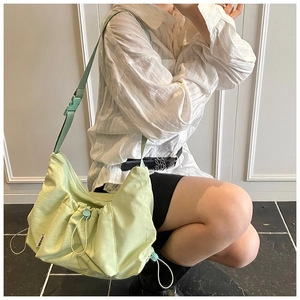 Detail of mint green pleated nylon tote bag featuring adjustable strap and side label