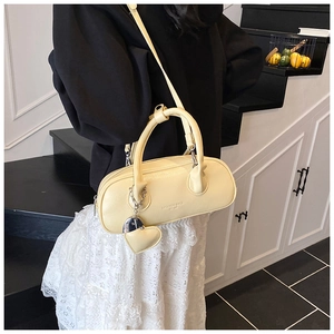 Vue détaillée du sac bowling crème avec gaufrage et détail de breloque en cœur