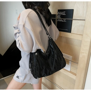 Detail of black pleated hobo bag with oil wax texture and silver tassel zipper