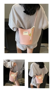 Sac seau rose à texture grainée avec pendentif d'ours doré et détails de corde tressée