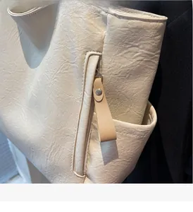 Detail of off-white lychee textured leather tote with smooth side zipper and long puller