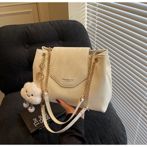 Detail of cream leather shoulder bag with gold chain strap and plush cloud charm