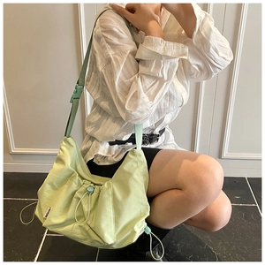 Detail of light green pleated nylon tote bag with drawstring and buckle strap
