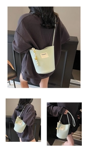 Gros plan d'un sac seau vert menthe en cuir grainé avec logo blanc et pendentif métallique