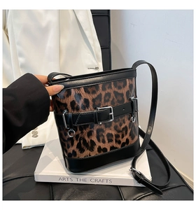 Gros plan du sac seau léopard avec lanières en cuir noir et boucle en métal dorée