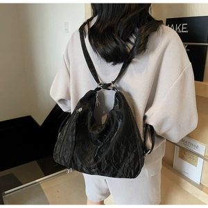 Close-up of black pleated texture bag with side zipper and metal buckle details