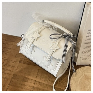 Detail of star-shaped buckle and lace ribbon on white faux leather messenger bag
