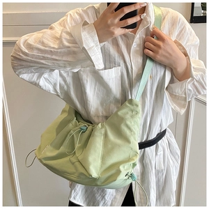 Detail of mint green drawstring crossbody bag with adjustable wide fabric strap