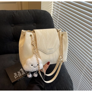 Detail of cream pleated shoulder bag featuring gold chain straps and a cloud charm