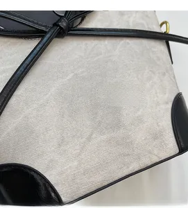 Detail of woven fabric texture with black leather trim and knotted strap on bucket bag