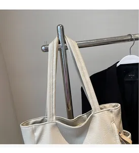 Detail of soft cream tote bag with natural pleated texture hanging on metal rack