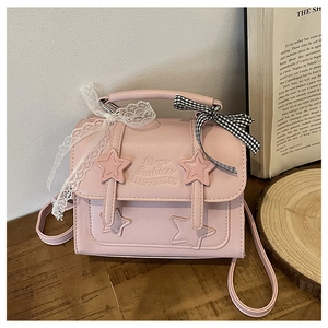 Detailed close-up of pink messenger bag with star appliqué, lace detail, and chic bow