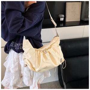 Detail of adjustable nylon shoulder strap and plastic buckle on the cream pleated tote bag