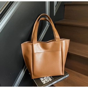 Close-up of a premium tan leather tote bag featuring a front pocket and soft texture