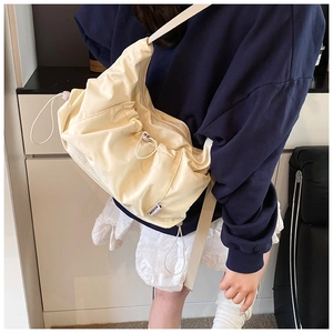 Detail of off-white nylon tote bag showing pleated texture and drawstring adjustment