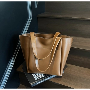 Detail of minimalist caramel tote bag with front pocket resting on a wooden step