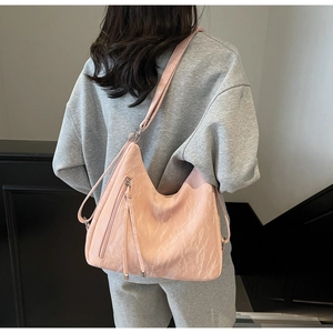 Detailed back view of model wearing a soft pink large hobo bag with fringe zip details
