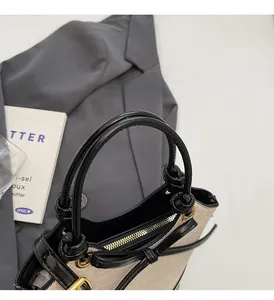 Close-up of beige canvas and black leather bucket bag with bow detail and gold zipper