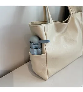 Detailed side view of beige tote bag showing side pocket with a small umbrella