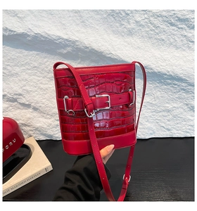 Détail du sac seau rouge en cuir embossé crocodile avec boucle argentée et coutures fines