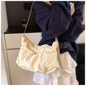 Detail of cream nylon tote bag featuring adjustable drawstring pocket and top zipper closure