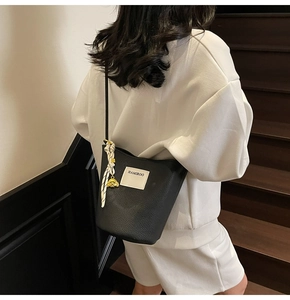 Détails du sac seau noir en cuir grainé avec foulard en soie et pendentif ours