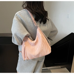 Detailed view of pink hobo bag with pleated texture and adjustable strap on model