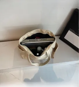 Detailed interior of a beige faux leather tote bag showing large capacity for laptop and books