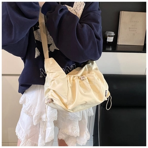 Detail view of cream nylon tote bag with drawstring adjustments and pleated texture