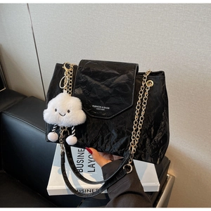 Close-up of black pleated faux leather bag with gold chain and white cloud plush charm